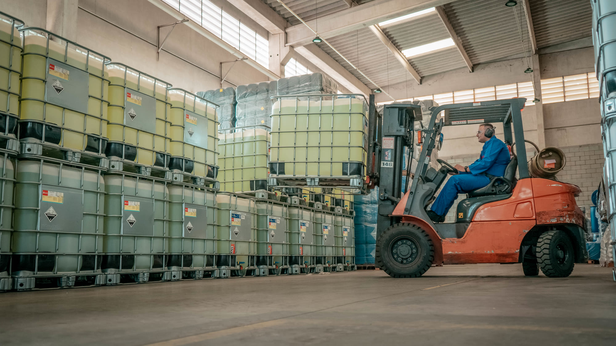 Operator moving chemical product tanks in Hanaoka's warehouse with a forklift